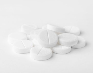 A heap of white medicine pills on white surface. clipart