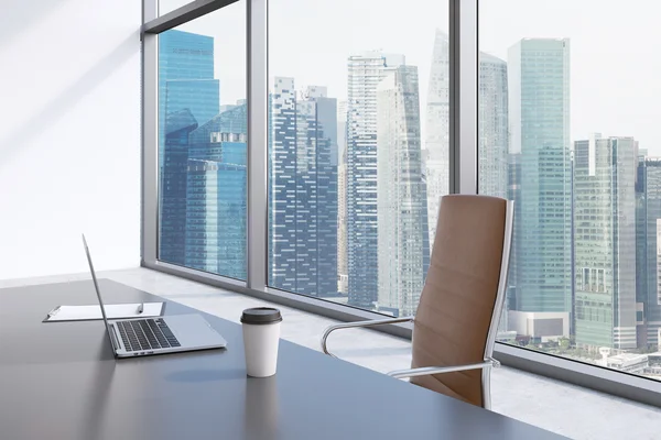 Un lugar de trabajo en una oficina panorámica moderna con vista a Singapur. Una mesa gris, silla de cuero marrón. Sobre la mesa hay un ordenador portátil, un bloc de notas y una tapa de café. Interior de oficina. Renderizado 3D . —  Fotos de Stock