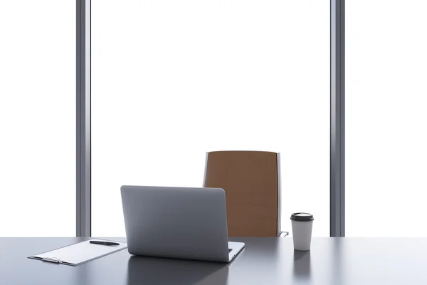 A workplace in a modern panoramic office with copy space in the windows. A grey table, brown leather chair. Laptop, writing pad and a cap of coffee are on the table. Office interior. 3D rendering. — 스톡 사진