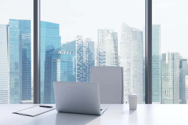 A workplace in a modern panoramic office with Singapore view. A white table, white leather chair. Laptop, writing pad and a cap of coffee are on the table. Office interior. 3D rendering. — стокове фото