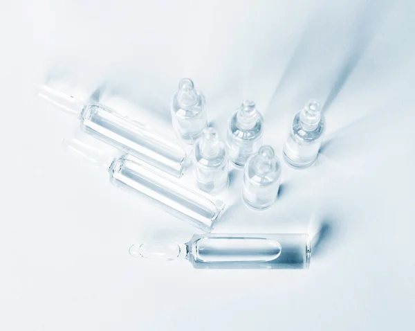 Top view of break-seal glass ampoule set with liquid medicine on light blue background. — 스톡 사진