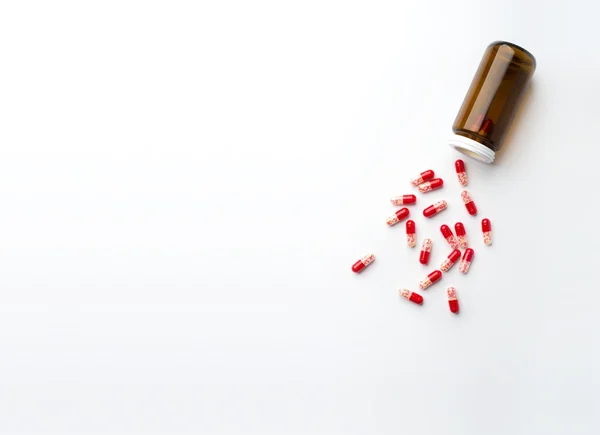 Top view of red Pills spilled from a bottle on surface. — Stock Photo, Image