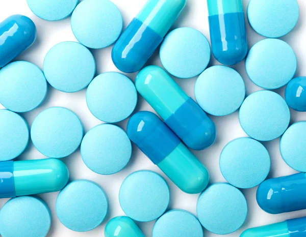 Медицинский фон с голубыми таблетками и голубыми капсулами — стоковое фото