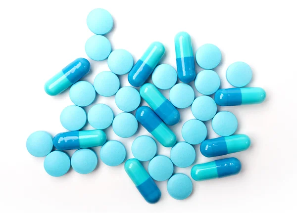 Spilled blue medicine capsules and pills on the white surface. — Stock Photo, Image