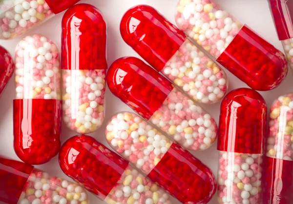 Close-up van de rode capsules op witte achtergrond. — Stockfoto