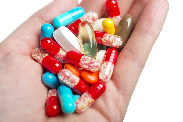 Een hand met gekleurde pillen en capsules. Geïsoleerd op witte achtergrond. — Stockfoto