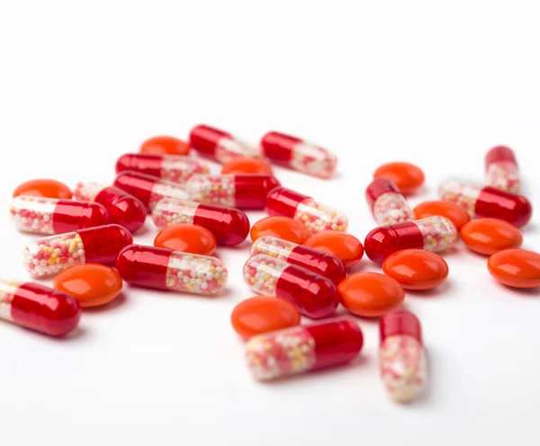 Cápsulas rojas derramadas, pastillas en la superficie blanca . —  Fotos de Stock