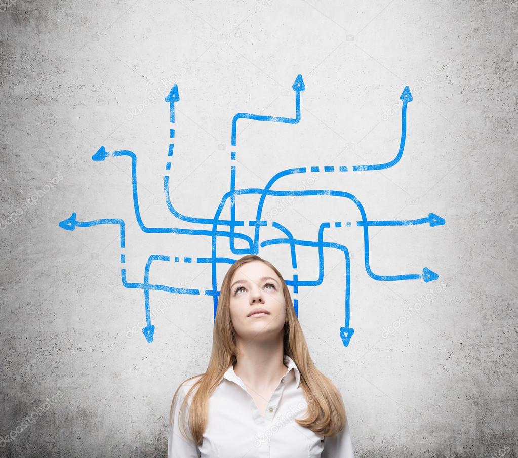 A beautiful young lady is pondering about possible solutions of the complicated problem. Many blue arrows with different directions are drawn around her head. Concrete wall as a background.