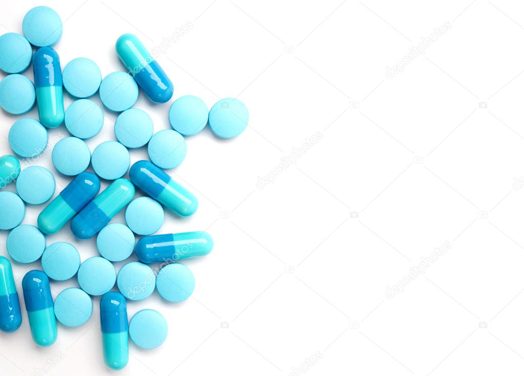 Spilled blue medicine capsules and pills on the white surface.