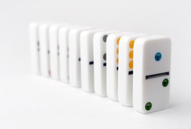The domino effect of white blocks, with colorful numbers. Selective focus on the front part of the domino blocks. White Background.