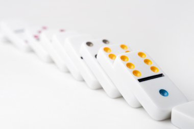 The domino effect of white blocks, with colorful numbers. Selective focus on the front part of the domino blocks. White Background.