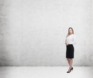 Full length beautiful lady in formal clothes. White shirt and black skirt. In a concrete wall.