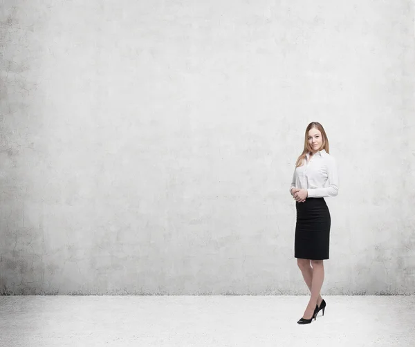 Full length beautiful lady in formal clothes. White shirt and black skirt. In a concrete wall. — Stock Photo, Image
