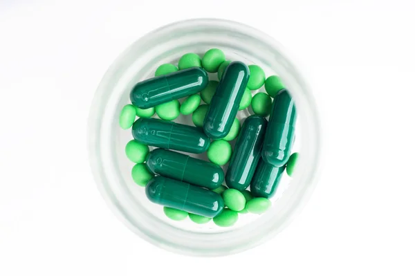 Green Pills and Capsules in a bottle. Isolated on white background. — Zdjęcie stockowe