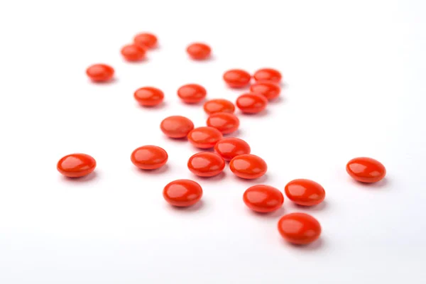 Kırmızı ilaç hapları bir yığın beyaz yüzey üzerinde bir yan görünüm. — Stok fotoğraf