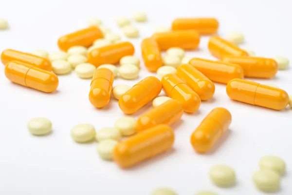 Kupie medycyna żółte tabletki i kapsułki na białej powierzchni. — Zdjęcie stockowe