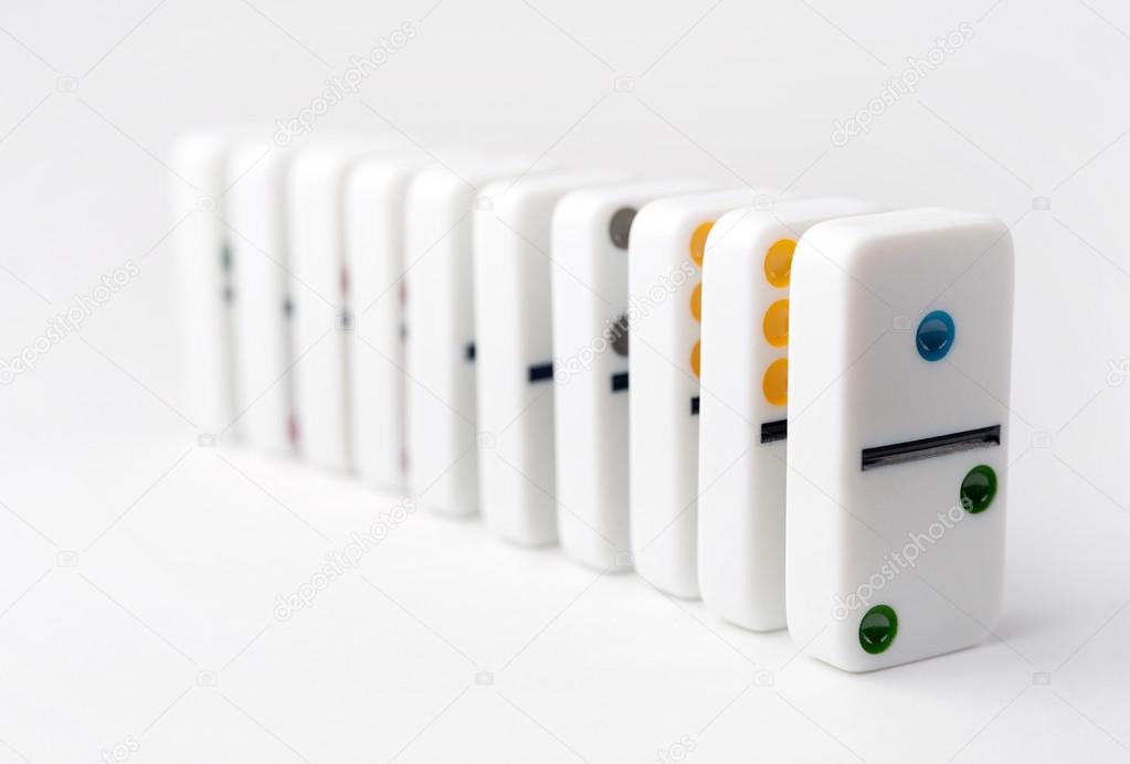 The domino effect of white blocks, with colorful numbers. Selective focus on the front part of the domino blocks. White Background.