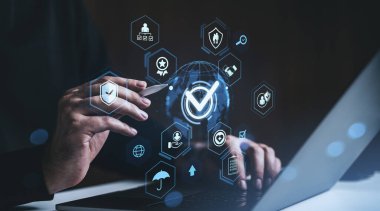 Hands of a businessman interacting with a glowing hologram of security icons and global network symbols over a laptop, on a dark blurred background, concept of digital compliance