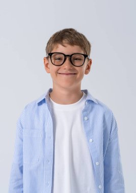 Gözlüklü ve çizgili tişörtlü mutlu çocuk kendine güvenen, doğal tarzda, aydınlık arka planda izole edilmiş, çocukluk ve kendine güven kavramı.