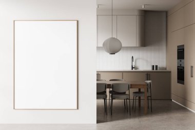Modern mutfak içinin beyaz duvarında büyük, dikey, boş poster çerçevesi yemek masası, kolye ışığı ve bej kabin. 3B Hazırlama