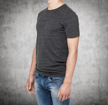 Side view of a man in a dark grey t-shirt and denims. Concrete background.