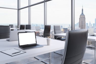 Workplaces in a modern corner panoramic office in Manhattan, New York City. White tables and black chairs. A laptop with a white screen, notepad and a coffee cup. 3D rendering.