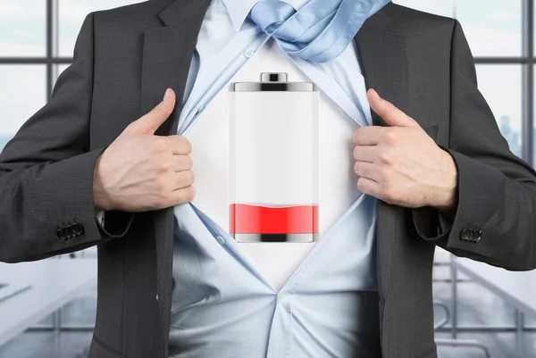 A man in a suit is tearing the blue shirt. Low level of power on the chest. Modern panoramic office background. — Stockfoto