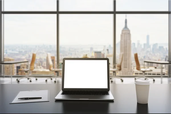 Vista frontal del lugar de trabajo en una moderna oficina panorámica en Nueva York. Mesas negras y sillas marrones. Una computadora portátil con una pantalla blanca, bloc de notas y una taza de café están sobre la mesa. Representación 3D. Imagen tonificada — Foto de Stock