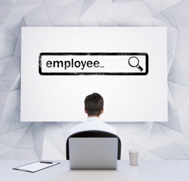 Rear view of a sitting person who looks at the whiteboard with the drawn searching bar with the word employee. A laptop, a writing pad and a cup of coffee are on the table.