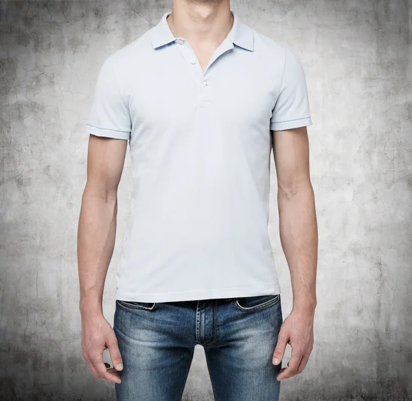 Front view of a man in a light blue polo shirt and denims. Concrete background. — Stock Photo, Image