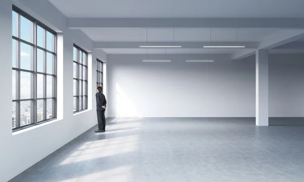 Full length a man in formal suit who is looking out the window in New York, modern loft style open space. — Stockfoto