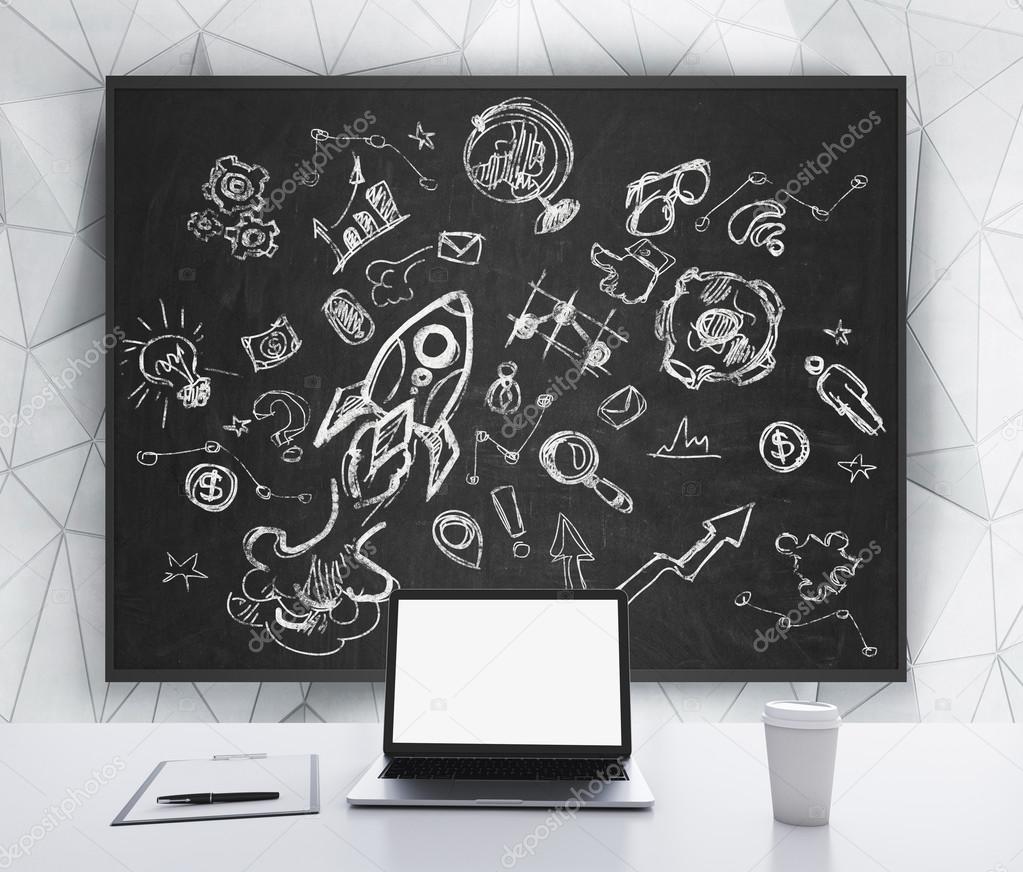A laptop with white screen, a writing pad and a cap of coffee are on the white table. Business or educational icons are drawn on the black chalkboard. 3D rendering.