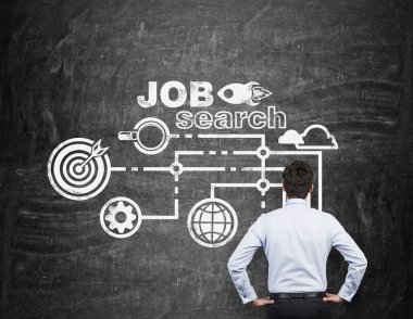 Rear view of a professional who is looking at the black chalk board with drawn icons about job search process.