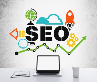 A workplace with a laptop with blank screen, a writing pad and a cup of coffee. A colourful SEO flowchart is drawn on the concrete wall. 3D rendering.