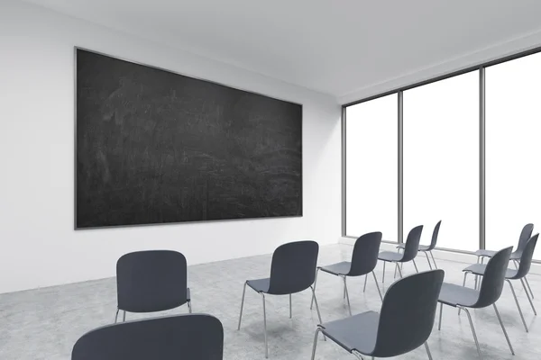 A classroom or presentation room in a modern university of fancy office. Black chairs, panoramic windows with white copy space and a black chalkboard on the wall. 3D rendering. — Stock fotografie