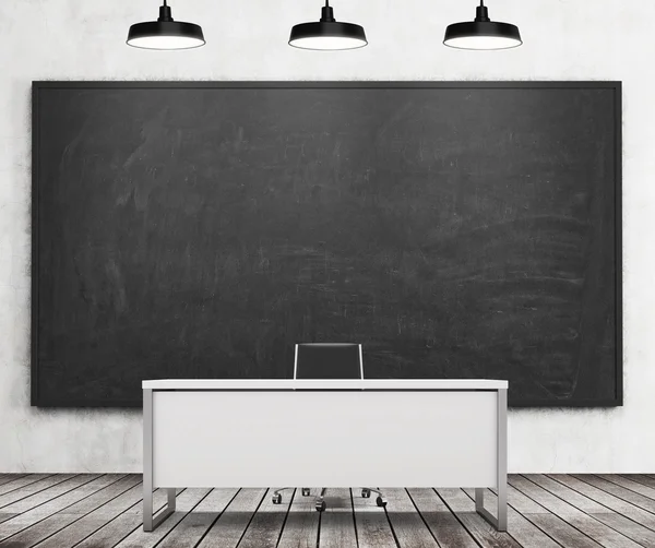 Teacher's or professor's desk in a modern university. A huge black chalkboard on the wall and three black ceiling lights, wooden floor. 3D rendering. — Stock fotografie