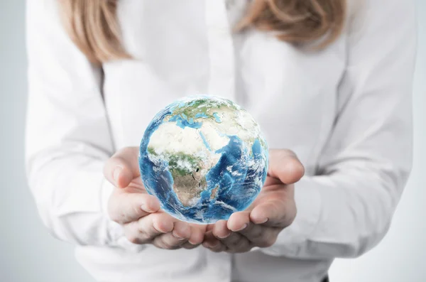 Close-up of blonde's hands who holds the globe with Africa, Europe and Asia hemisphere. A woman dressed in formal clothes. A light grey background. Elements of this image furnished by NASA. — Φωτογραφία Αρχείου