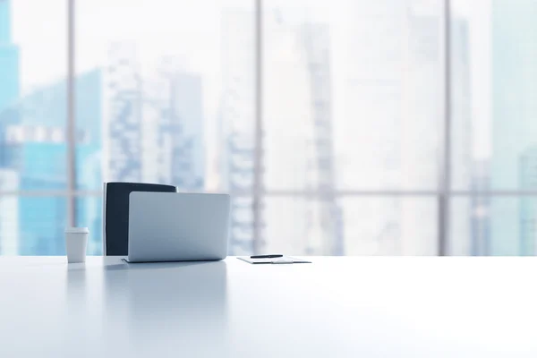 A workplace in a modern panoramic office in Singapore. A laptop, notepad and a coffee cup are on the white table. 3D rendering. — Stock fotografie