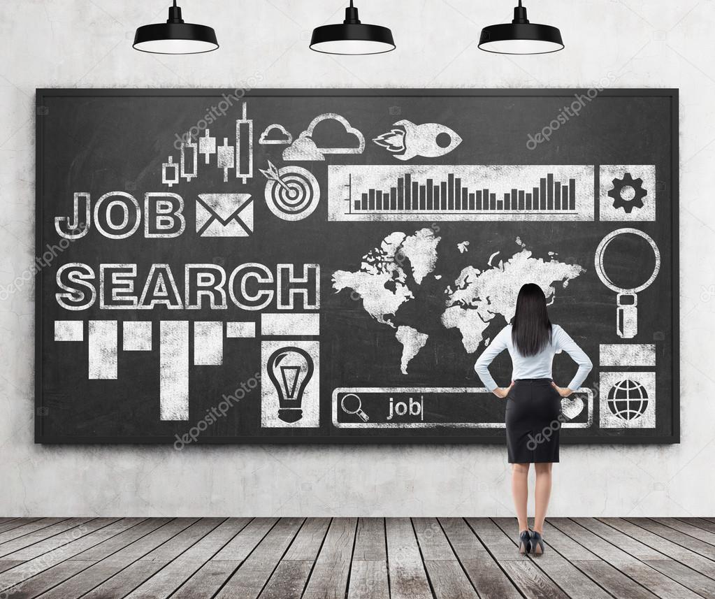 Rear view of a brunette lady in formal clothes who is looking at the huge black chalk board with drawn icons about job search process. Wooden floor and concrete wall.