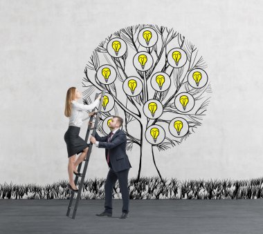 A man in formal suit holds a ladder for the business lady who climbs up the sketched tree with light bulbs. Concrete background.