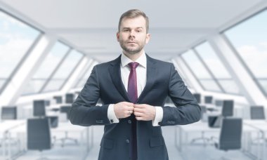 A handsome professional is buttoning up the suit. Bright modern panoramic roof loft office. The concept of luxury consulting services.
