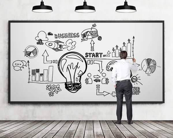 Full length rear view of businessman in formal clothes who is drawing a business flowchart on the whiteboard. Concrete wall, wooden floor and four black ceiling lights in the room. — ストック写真