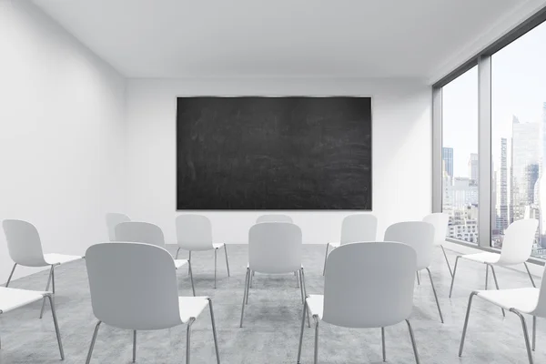 A classroom or presentation room in a modern university or fancy office. White chairs, a black chalkboard on the wall and panoramic New York view. 3D rendering. — Stock fotografie