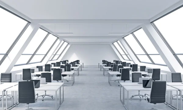 Workplaces in a bright modern open space loft office. White tables equipped by modern laptops and black chairs. White copy space in the panoramic windows. 3D rendering. — Stockfoto