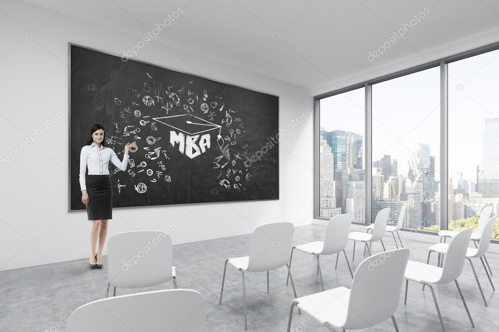 A brunette makes a presentation in a classroom in a modern university or fancy office. White chairs, a black chalkboard on the wall with MBA sketch and panoramic New York view.