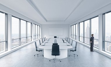 A Businessman is looking out the window in a modern panoramic meeting room in New York. The concept of the meeting of the Board of Director of the huge transnational corporation.