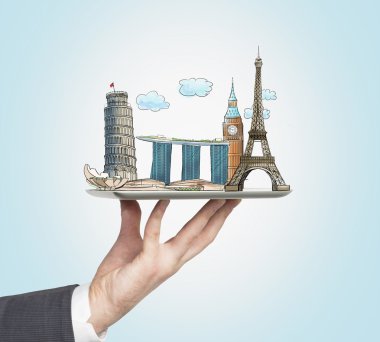 A man's hand holds a tablet with sketches of the most famous places in Italy, Great Britain, France and Singapore. The concept of tourism and sightseeing. Light blue background.