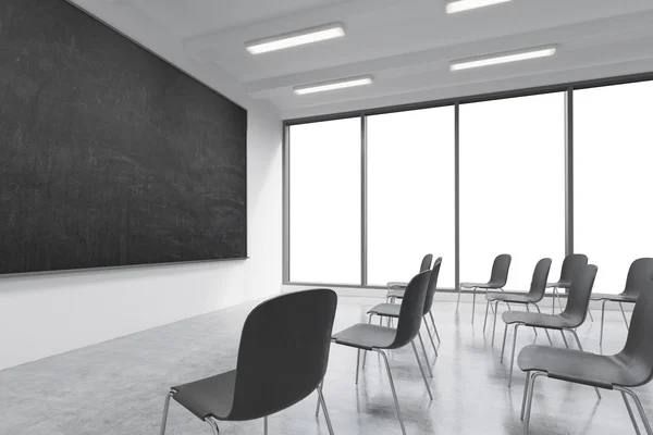 A classroom or presentation room in a modern university or fancy office. Black chairs, a black chalkboard on the wall and panoramic windows with white copy space. 3D rendering. — 스톡 사진