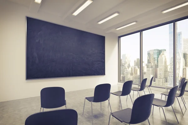 A classroom or presentation room in a modern university or fancy office. Black chairs, a black chalkboard on the wall and panoramic windows with New York view. 3D rendering. Toned image. — Stok fotoğraf