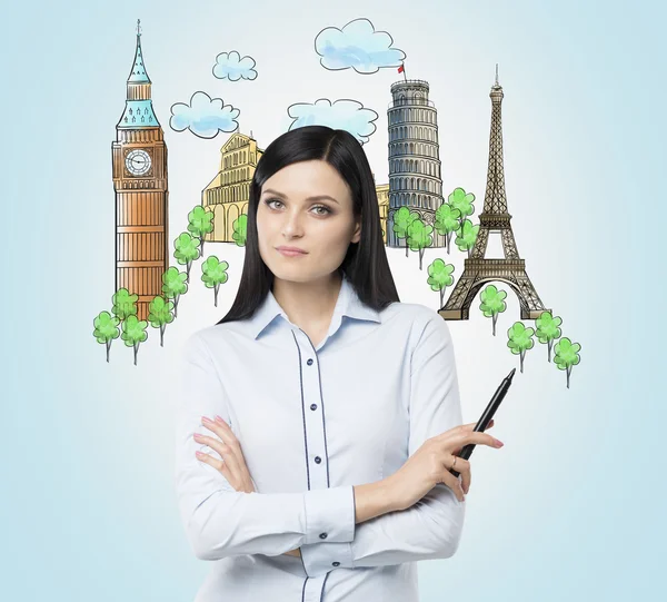 A brunette woman offers the visiting of the most famous cities in Europe. The concept of tourism and sightseeing. Light blue background. — Stock Fotó